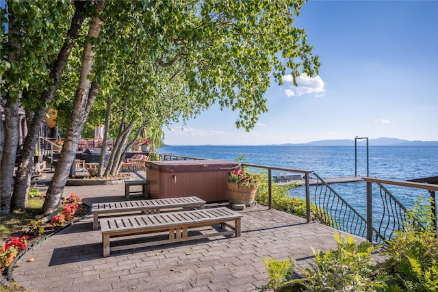 view of patio / terrace with a hot tub and a water and mountain view