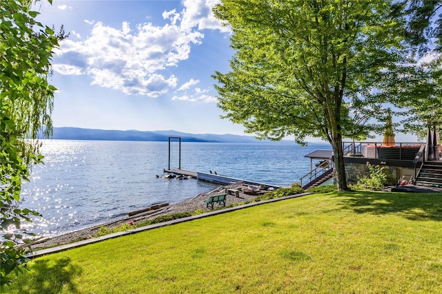 exterior space featuring stairs, a water and mountain view, and a yard