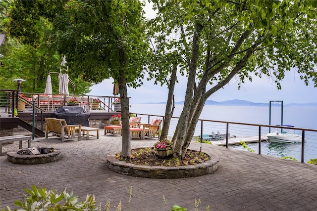 view of patio with a boat dock, a grill, a fire pit, and a water and mountain view