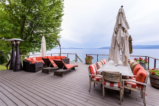 wooden terrace with outdoor dining space and a water and mountain view