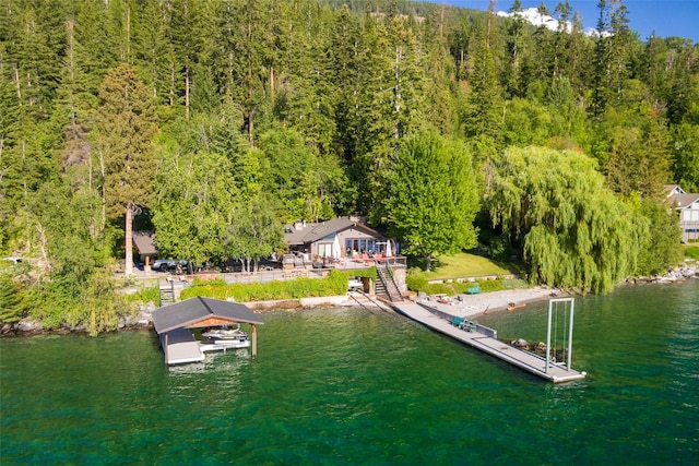 birds eye view of property featuring a water view and a wooded view