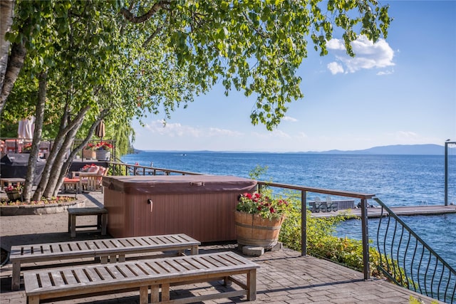 exterior space with a hot tub and a water and mountain view