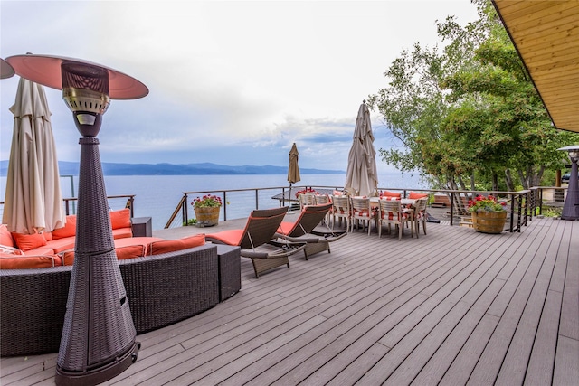 wooden terrace with a water view, outdoor dining area, and an outdoor living space