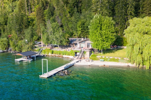 dock area with a water view, a wooded view, and stairs