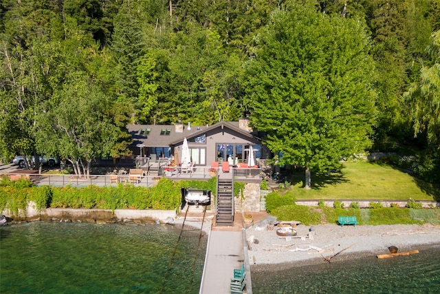 view of front facade with a water view, a chimney, and stairs