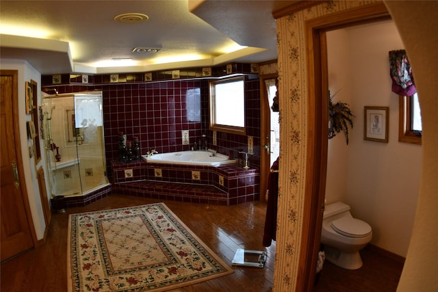 bathroom featuring toilet, a stall shower, wood finished floors, baseboards, and a bath