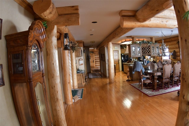 dining space featuring light wood-style floors, rustic walls, and beam ceiling