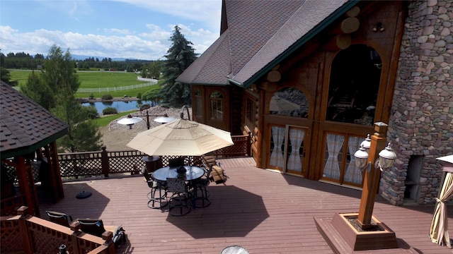 wooden deck featuring outdoor dining space, french doors, and a water view