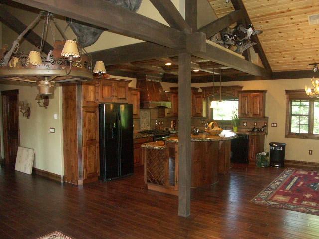 kitchen featuring black appliances, custom range hood, brown cabinetry, and dark wood-type flooring