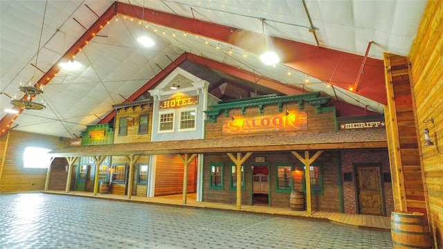 interior space with high vaulted ceiling, wooden walls, and brick wall