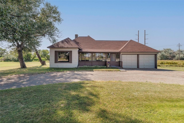 view of front of home featuring a shingled roof, gravel driveway, an attached garage, and a front lawn