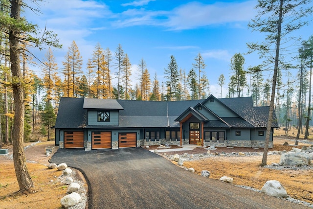 view of front of home featuring driveway, stone siding, a garage, and french doors