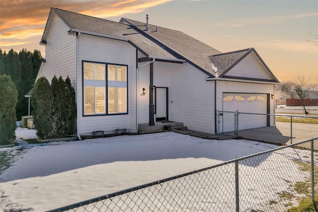 view of front of property featuring concrete driveway, roof with shingles, an attached garage, and fence