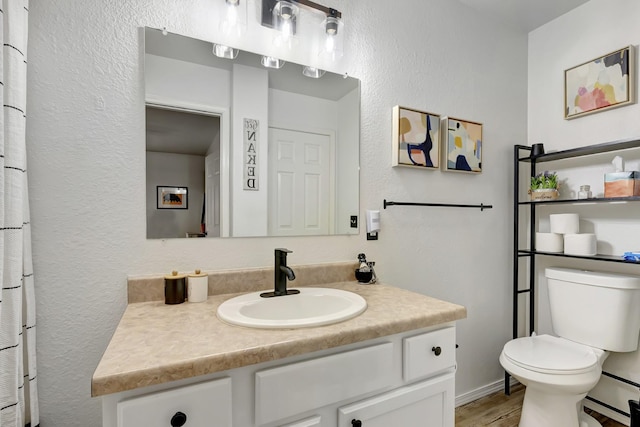 bathroom with a textured wall, toilet, a baseboard heating unit, vanity, and wood finished floors