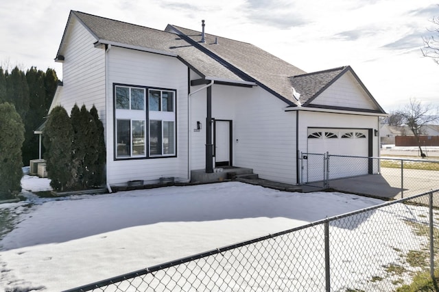 view of front of home with a garage, concrete driveway, roof with shingles, and fence