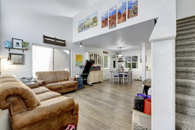 living area featuring a high ceiling, light wood finished floors, and stairs