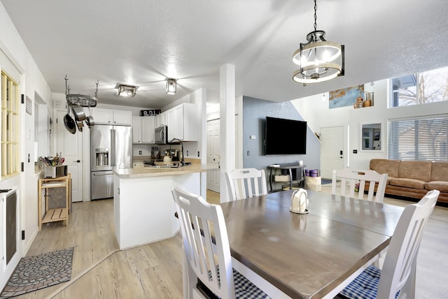 dining room with light wood finished floors, a textured ceiling, and a notable chandelier