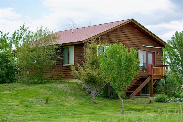 exterior space featuring metal roof, stairway, a front yard, and a wooden deck