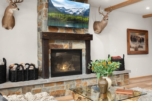 interior details with beamed ceiling, a fireplace, and wood finished floors