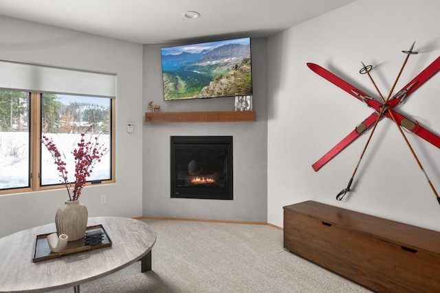 carpeted living area with a glass covered fireplace and baseboards