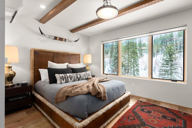 bedroom featuring multiple windows, beamed ceiling, and wood finished floors