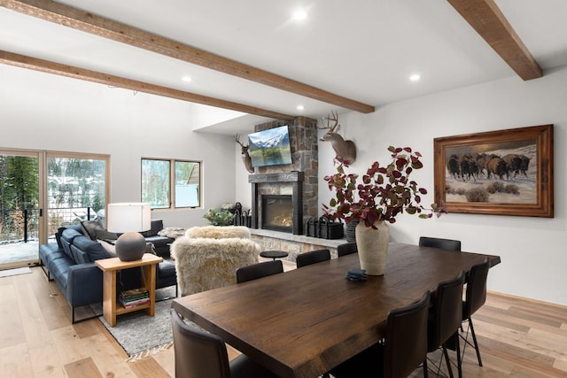 dining area featuring recessed lighting, light wood-style flooring, beamed ceiling, and a stone fireplace