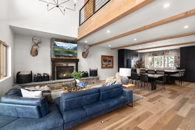 living area with light wood-style flooring, a notable chandelier, recessed lighting, a fireplace, and beam ceiling