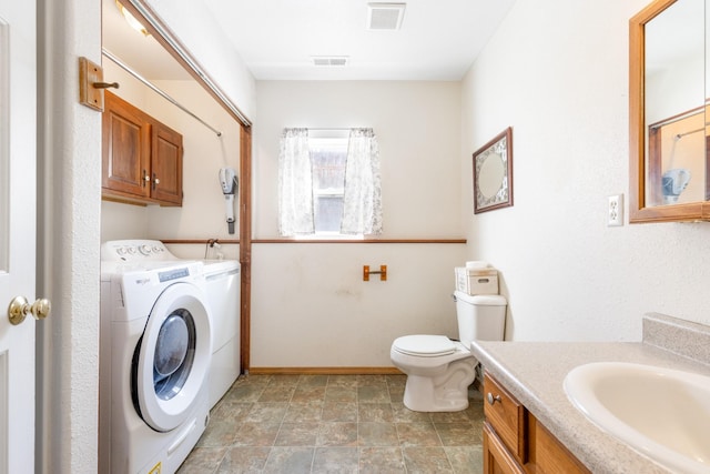 bathroom with toilet, vanity, washing machine and dryer, and visible vents