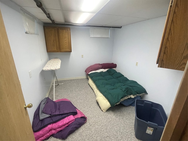 carpeted bedroom featuring a paneled ceiling and baseboards