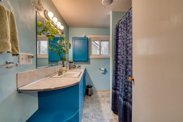 full bath featuring curtained shower, vanity, and baseboards