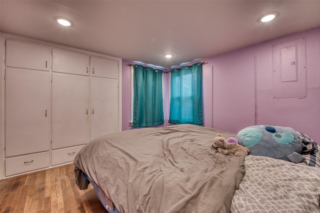 bedroom with light wood-style floors, electric panel, a closet, and recessed lighting