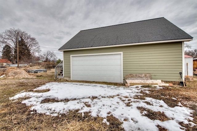 snow covered garage with a detached garage