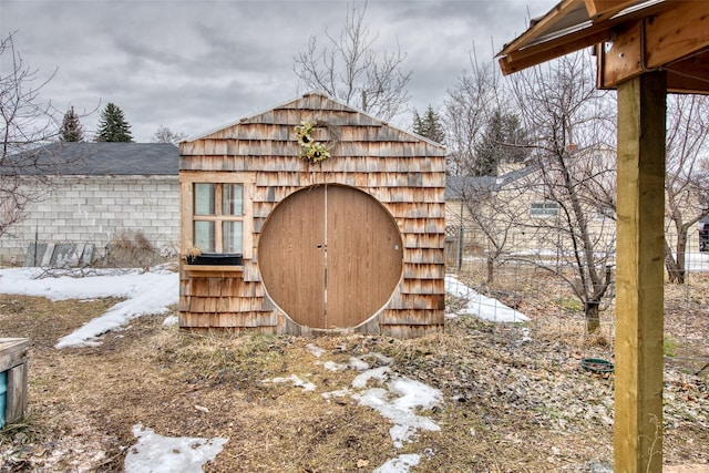 snow covered structure with a storage shed and an outdoor structure