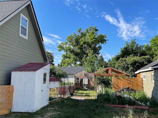 view of yard featuring a storage unit, an outdoor structure, and fence