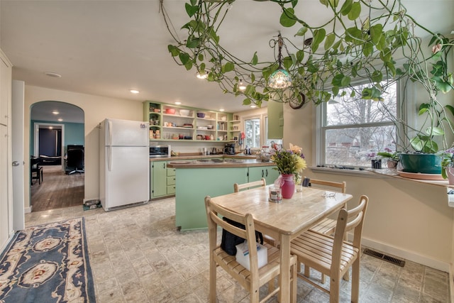 dining area with baseboards, visible vents, arched walkways, and recessed lighting