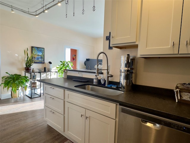 kitchen featuring a peninsula, a sink, dishwasher, dark countertops, and dark wood finished floors