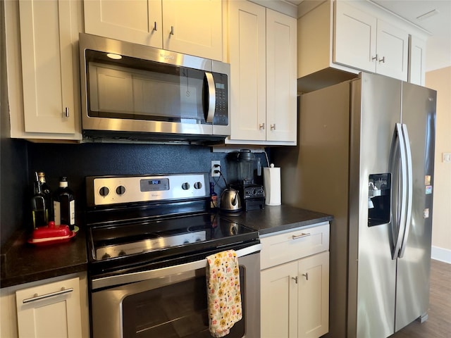 kitchen featuring appliances with stainless steel finishes, dark countertops, and white cabinetry