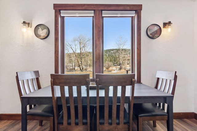 dining space with baseboards and wood finished floors