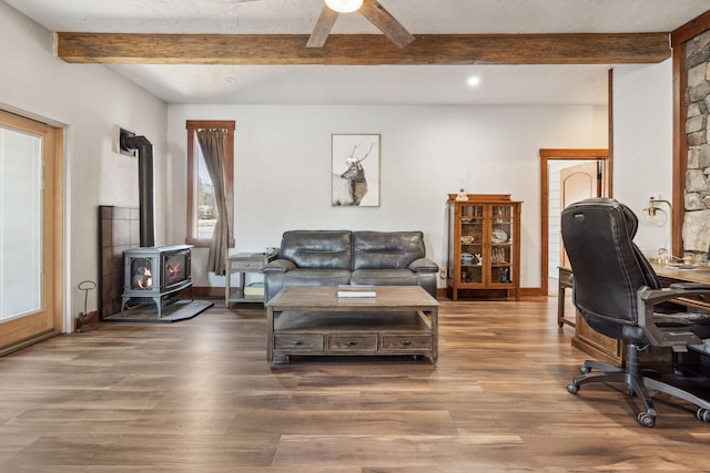 office featuring beam ceiling, a wood stove, and wood finished floors