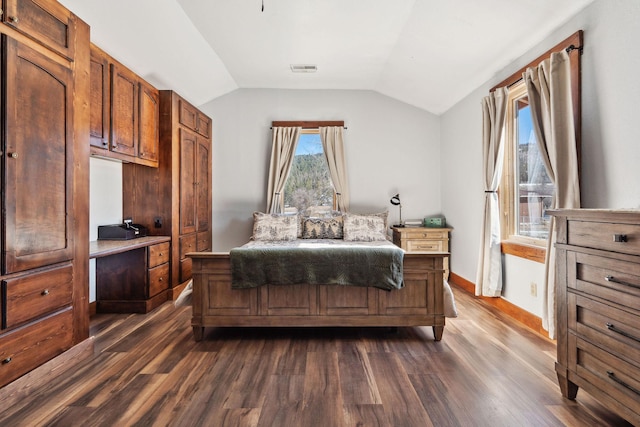 bedroom with dark wood finished floors, vaulted ceiling, and baseboards