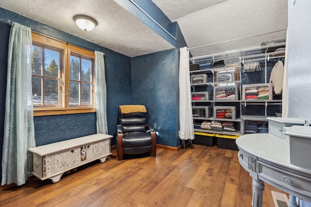 sitting room with a textured ceiling, baseboards, and wood finished floors