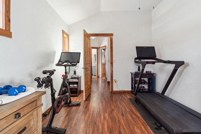 exercise room with vaulted ceiling, dark wood finished floors, and baseboards