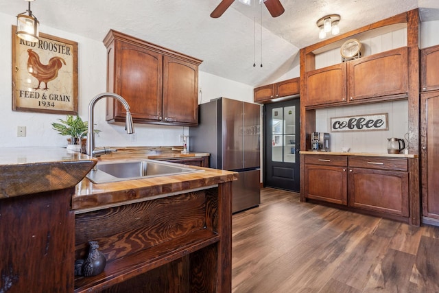 kitchen featuring dark wood-style floors, lofted ceiling, freestanding refrigerator, a sink, and ceiling fan