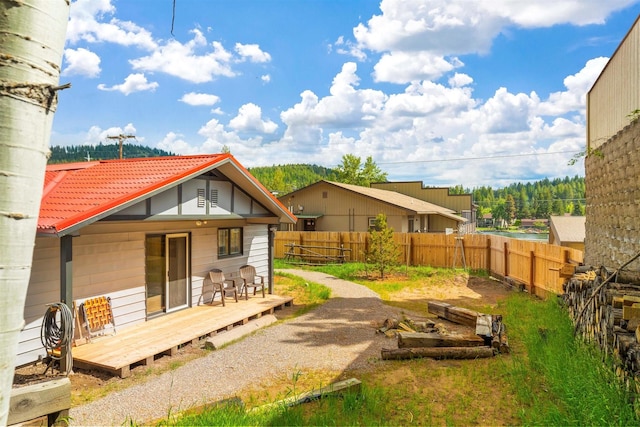 back of property with a tile roof, fence, and a wooden deck