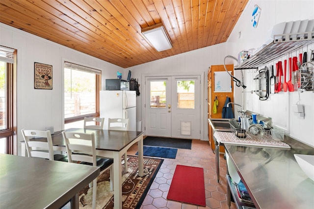 kitchen featuring wood ceiling, stainless steel counters, freestanding refrigerator, and a healthy amount of sunlight