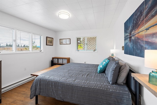 bedroom with baseboard heating and wood finished floors