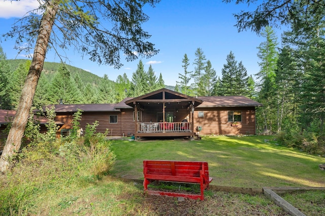 rear view of house featuring a deck with mountain view and a yard