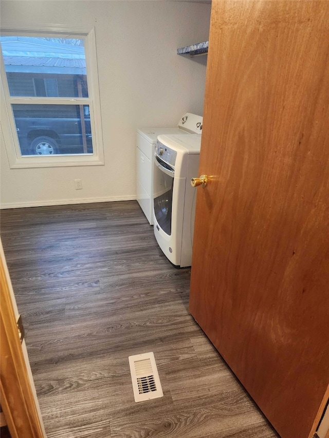 clothes washing area featuring dark wood-style floors, visible vents, washer and dryer, laundry area, and baseboards