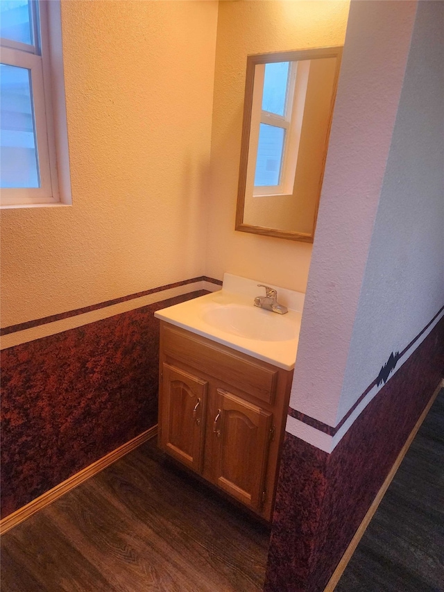 bathroom featuring plenty of natural light, vanity, baseboards, and wood finished floors