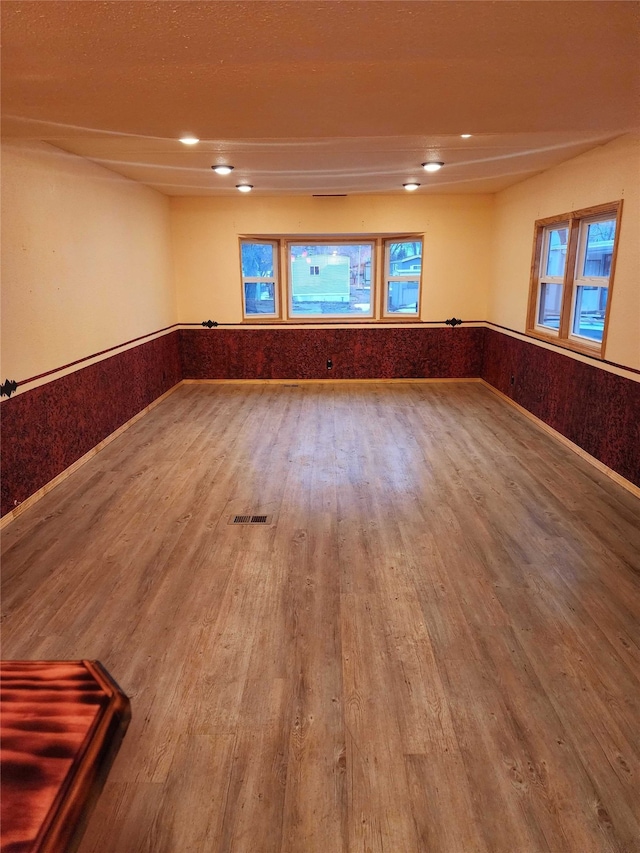 empty room with a wainscoted wall, wood finished floors, and recessed lighting